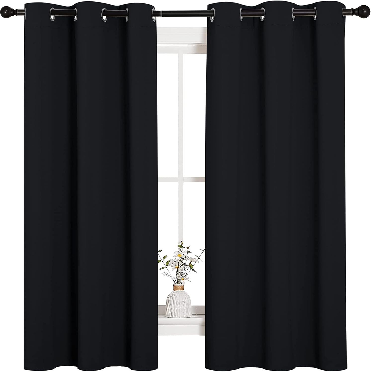 Pair of black NICETOWN thermal insulated grommet blackout curtain panels hanging at a bedroom window